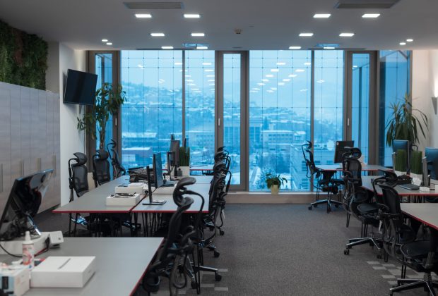 Front view of coworking office interior with workplaces, blank picture frame on wall and computer. . High quality photo